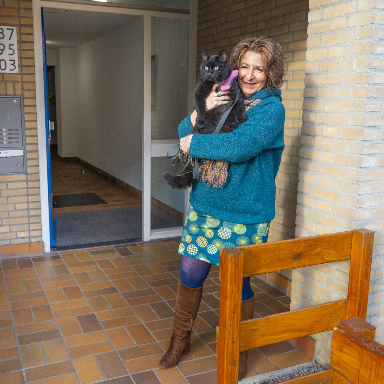 Nicole Noordman staat met haar kat voor de voordeur van haar appartement.