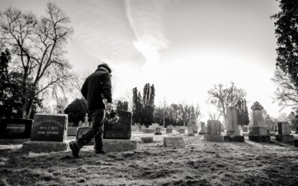 Oude man loopt voorbij een aantal graven op een begraafplaats