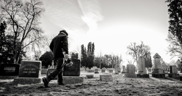 Oude man loopt voorbij een aantal graven op een begraafplaats