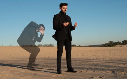 Wahhab Hassoo staande op het zand, biddend richting de zon