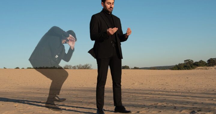 Wahhab Hassoo staande op het zand, biddend richting de zon