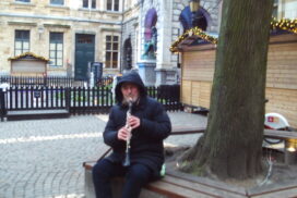 Klarinettist op Hendrik Conscienceplein Antwerpen. Een gedeelte van de kerstmarkt kramen is ook zichtbaar.